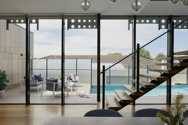 Salón con escalera de diseño y vistas a la piscina