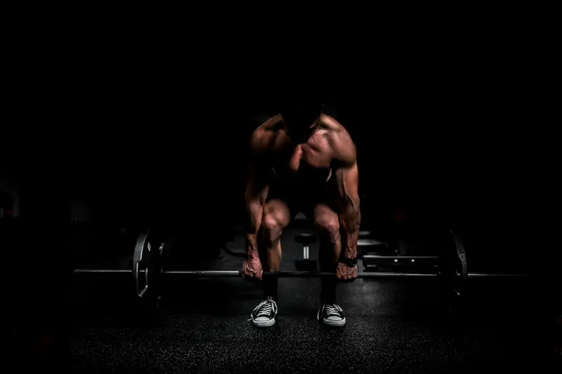 Atleta levantando una barra en un gimnasio a oscuras