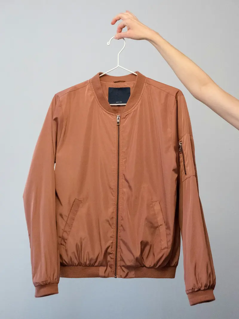 Cazadora bomber color salmón en una percha