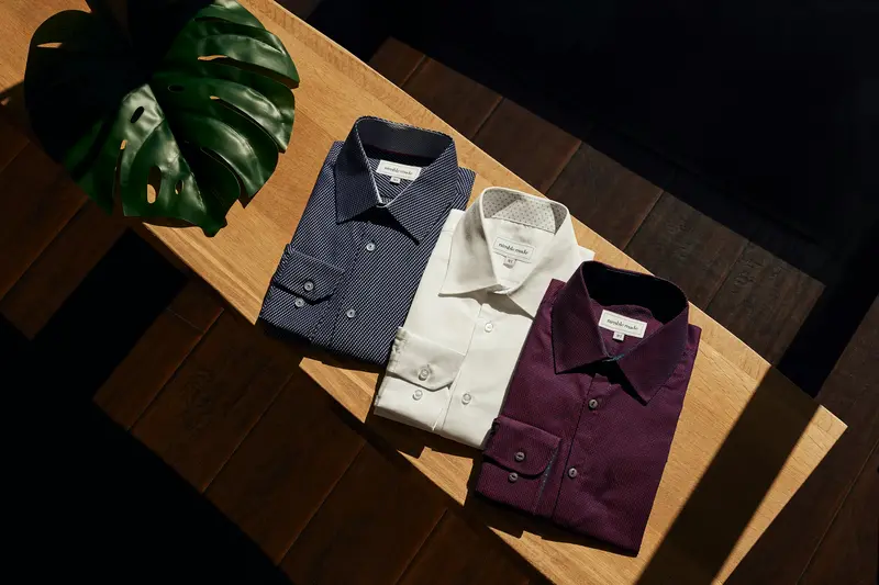 Tres camisas dobladas en tonos claros y burdeos