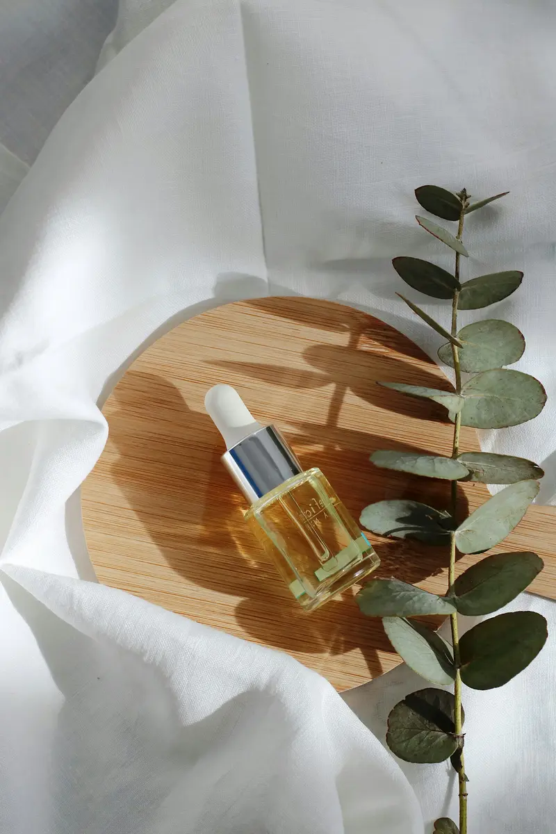 Cuentagotas con aceite sobre madera junto a hojas de eucalipto