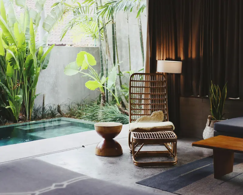 Zona de descanso con plantas, butaca de mimbre y piscina interior