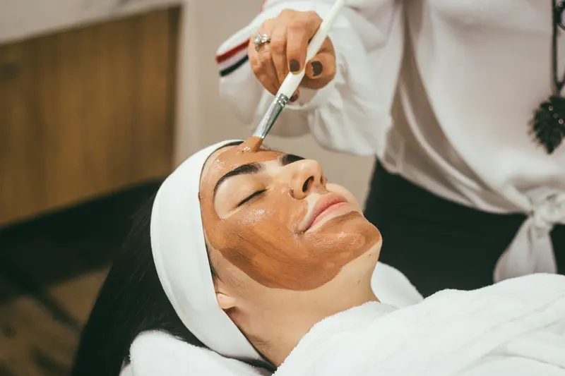 Aplicación de mascarilla con pincel durante un tratamiento facial