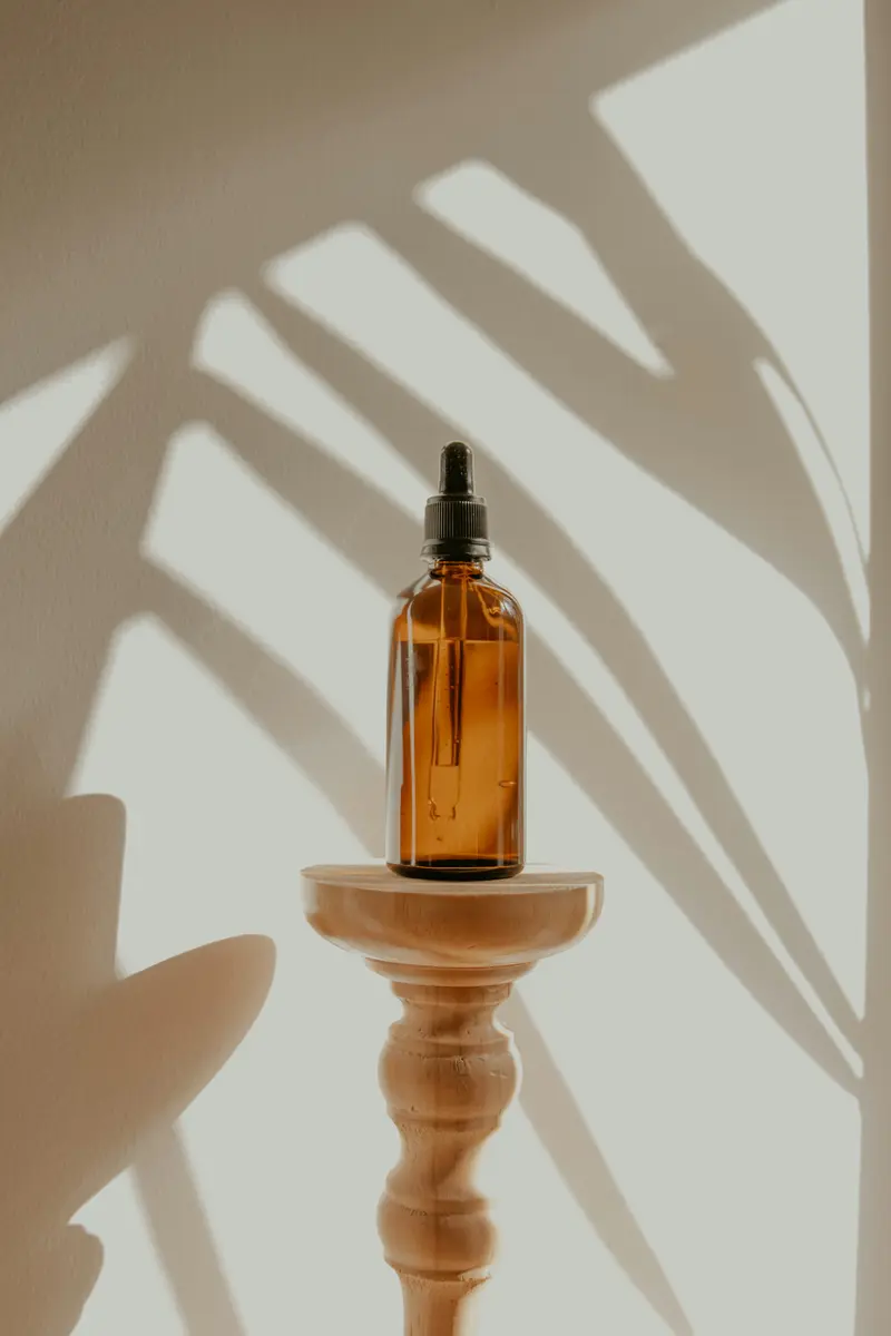 Frasco de aceite ámbar sobre un pedestal con luz natural