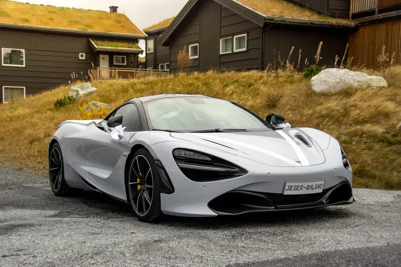 McLaren 720S blanco aparcado frente a casas de madera