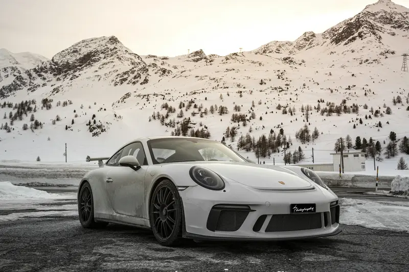 Porsche 911 GT3 blanco con alerón en una carretera de montaña nevada