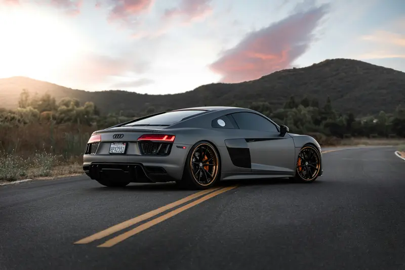 Audi R8 gris en una carretera al atardecer